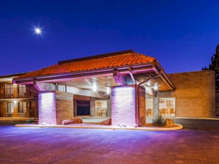 A well-lit entrance of a building with a red-tiled roof and pillars, against a night sky with a shining star.