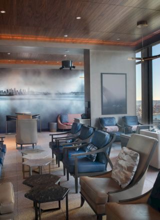 A modern lounge area with ample seating, large windows offering a scenic view of a waterfront and a Ferris wheel, and contemporary decor.