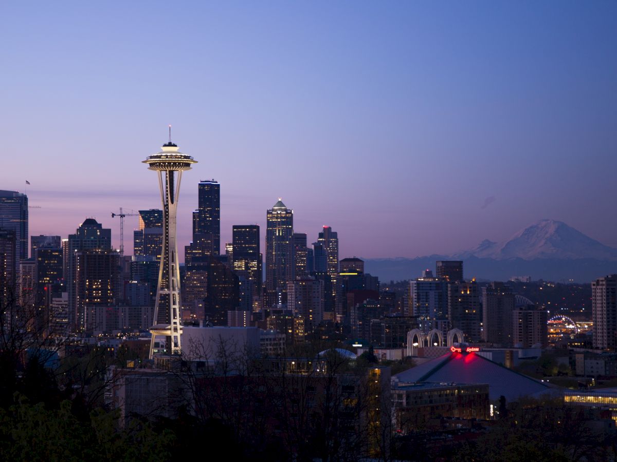 This image shows the Seattle skyline at dusk with the Space Needle prominently visible and Mount Rainier in the background.
