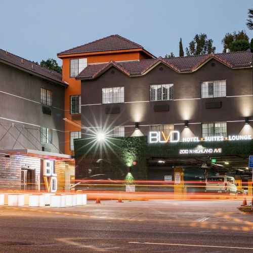 A modern hotel at night with lights on the building and blurred street traffic, featuring a sign for 